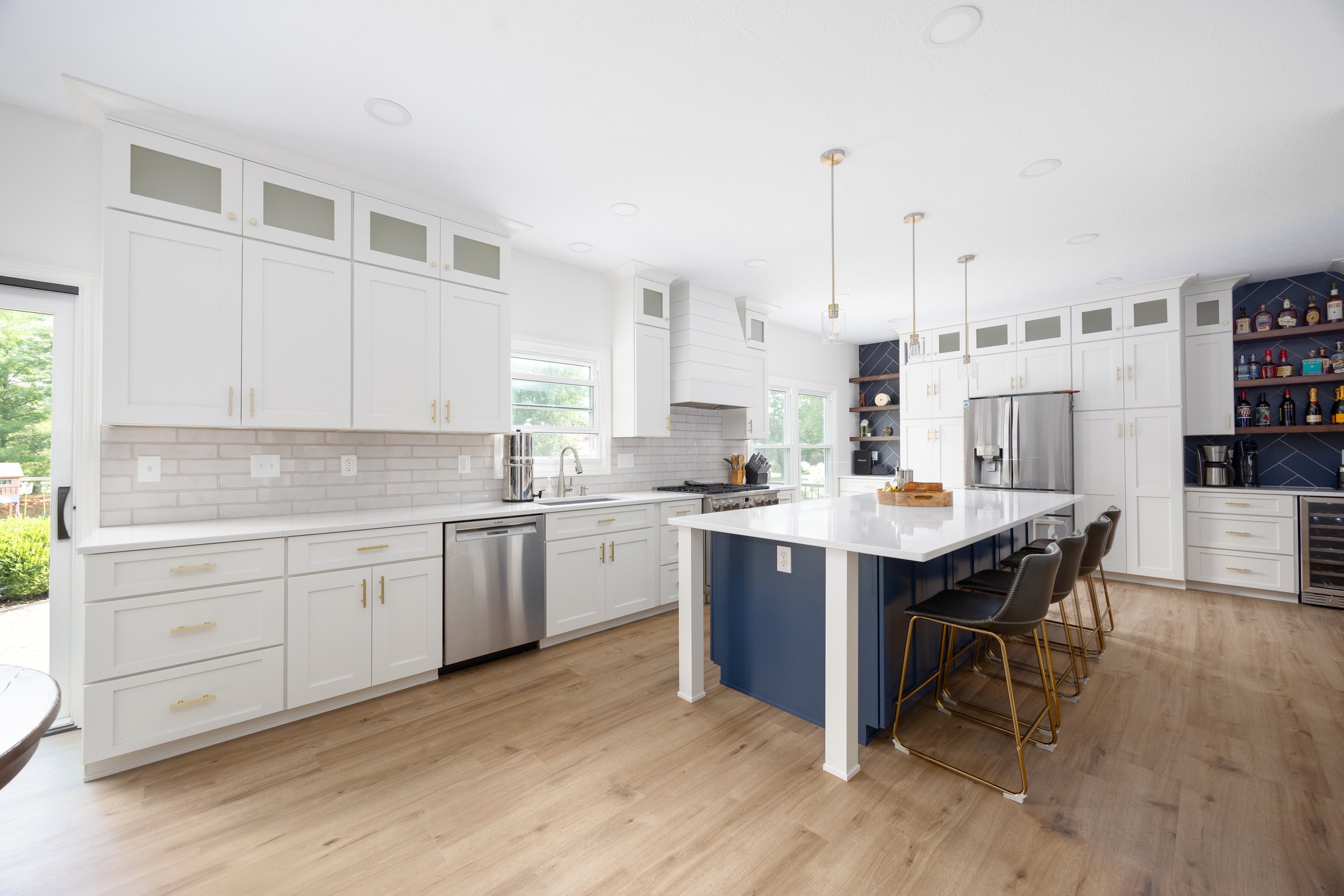 Remodeled kitchen with painted island, quartz counters and brass pendant lighting